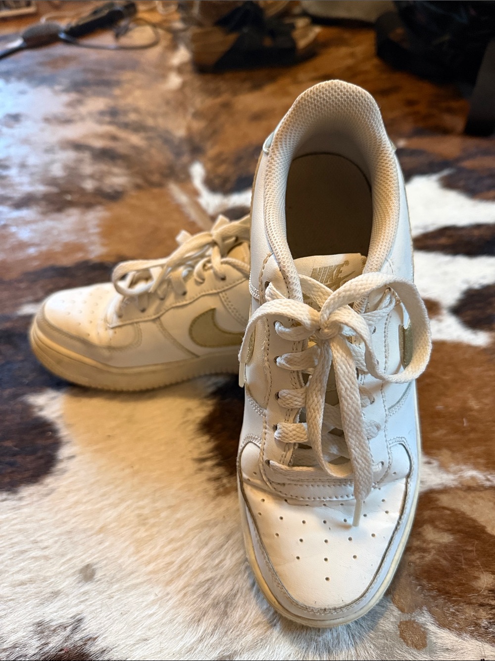 Nike low top Air Force ones. All white with gold swoosh.